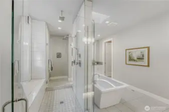 The spa-inspired en suite features a freestanding Maax soaking tub, skylight, and a glass-enclosed walk-in shower with dual entrances, double rain shower heads, wand, and a long bench.