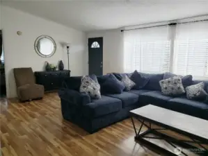 A View of the Enormous Open Living Room with Cathedral Ceiling, Newer Laminate Flooring Looking at the Front Entry Door.