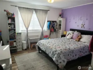 A Picture of the Spacious Second Bedroom with Newer Paint, Trim, and Vinyl Plank Flooring.
