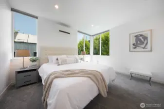 Airy and serene, the primary bedroom features tree-lined views.