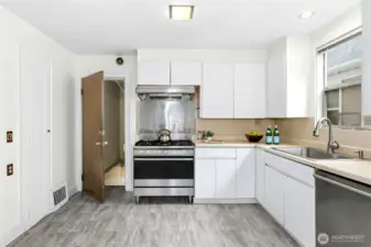 The kitchen has a Fisher & Paykel 5-burner gas range with a center burner that does both fast boil and low simmer, lots of cabinet storage, including a spice pantry to the left. The door leads to the daylight, partially finished basement.