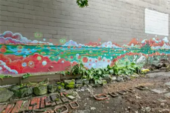 The Michael O'Driscoll mural spans across the wall--the wall is to the adjacent warehouse and provides a lovely shield from the noise and hot sun. The garden bed along the wall has calla lilies that are spectacular in the spring.