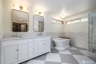 The private primary suite bathroom has tile and marble flooring, tile wainscoting, double vanity, a deep soaking tub, and spacious tile and marble shower.