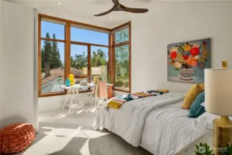 A bright second bedroom with oversized windows and a versatile layout ideal for work or rest.