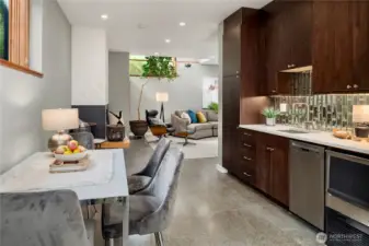 Wet bar with dishwasher, ice maker, full-size fridge, modern cabinetry and stylish backsplash enhances everyday convenience.