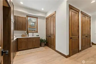 Large laundry room with built in cabinetry and convenient sink. Back stair case leads to bonus room and hallway to garage.