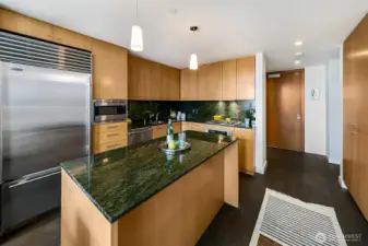 Huge kitchen island with beautiful granite slab counters and backsplash.