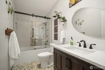 Fully remodeled upper bath showcasing custom tile, tub/shower, frameless glass shower door, and modern hands-free flush toilet.