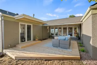 Two sets of French doors open onto a brand-new deck, seamlessly extending the living room and kitchen spaces outdoors.