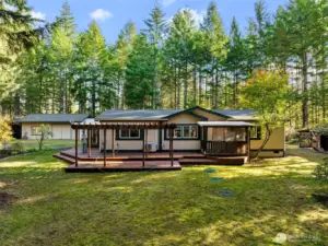 Sitting on 1.21 secluded acres,  fully fenced with gate, covered entry both front and back. Extensive decking surrounds home, ideal for outdoor living.  Large detached garage shop with carport and ample shed as well.