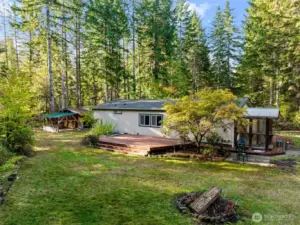 Side view shows ample deck and woodshed behind home.