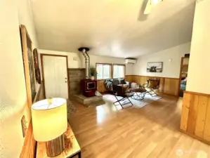 Welcome,  entry into living room with laminate flooring, wood stove and charming knotty pine wainscoting.