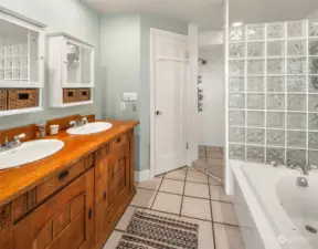 The primary bathing area with soaking tub and tiled walk-in shower. W/C has it's own private room with pedestal sink.