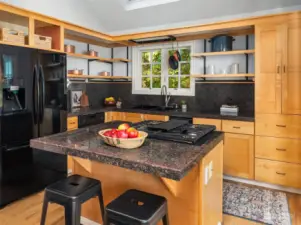 The kitchen is efficient and light-filled with lots of open shelving, an eating bar, french doors onto the deck and a huge skylight.