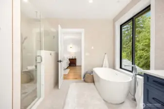 Primary bathroom: Luxurious Spa-like bathroom with freestanding slipper tub, Twin vanities set in a quartz countertop with ample navy blue cabinetry, Tile walk-in shower for two with four shower heads, Floor-to-ceiling ceramic tiled walls add to the high-end feel of this peaceful bathroom retreat, Heated tile floors...