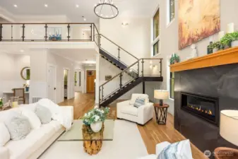 Architectural floating I-beam staircase with glass panels leads to second story; Quartz topped desk niche in great room area