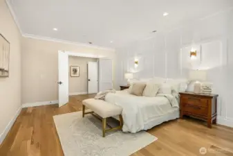 This angle of the primary suite shows off the beautiful wainscoting on the walls and wall sconces for different lighting options.