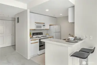The kitchen features bar seating. Laundry closet in the background.