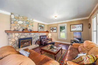 Step into comfort! The cozy living room features a stunning river rock fireplace with insert, creating the perfect gathering space. Large windows frame breathtaking views in every direction—bringing the beauty of the outdoors in.