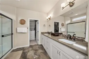 Primary bathroom with Quartz counters, two undermount sinks, oil rubbed bronze hardware, tiled floors and a large walk-in with built-in closets.