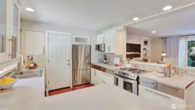 A light filled culinary space with sleek white cabinetry and seamless garage access.