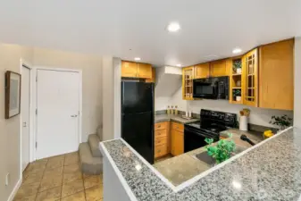 Open kitchen with tile floors, concrete counters, and great cabinet space. In-unit W/D in the closet on the left.