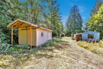 Shed on left is in good shape. Manufactured home on property is a tear-down, DO NOT attempt to enter. This space is a good sized level area for a big rambler.