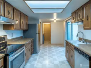 Kitchen with view into laundry room and slider on right to exterior patio area.