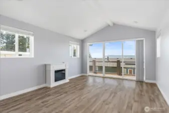 Primary bedroom w/ electric fireplace and deck access.
