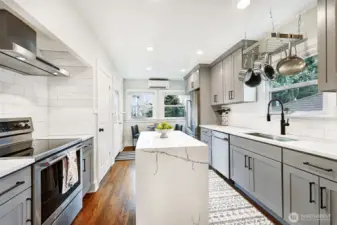 Remodeled kitchen with island, stainless KitchenAid appliances, subway tile, quartz counters and plenty of cabinets/storage and workspaces. Cozy eating space overlooks backyard gardens and patio. Access door to backyard from kitchen.