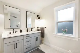 Primary (ensuite) bathroom with double sinks, tile floor and tub surround.