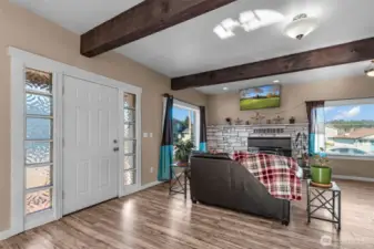 Front entry and living room with woodstove insert and exposed wood beams, lots of natural lighting