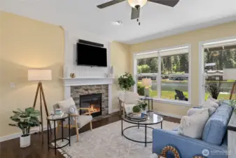 A cozy and inviting living room, featuring a warm fireplace, hardwood floors, and bright tones that create a relaxing space for family gatherings or quiet nights in. Perfect for unwinding after a long day.