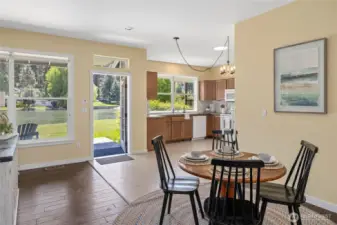Bright dining and kitchen area with scenic water views, natural light, warm wood cabinetry, and seamless indoor-outdoor flow.