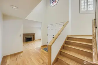 The staircase angles from the front entry, leading you to the upper level. It is brightly lit with soaring ceilings and a wall of windows.