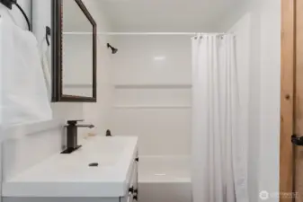 Fresh tub/shower combo with updated fixtures and classic white surround.