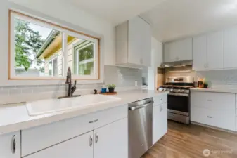 Convenient kitchen setup with stainless steel dishwasher and window overlooking the backyard.