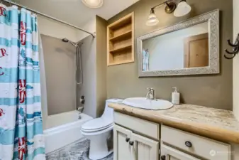Upstairs main full bathroom features slate flooring, white cabinets and a skylight.