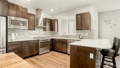 Kitchen offers stainless steel appliances, rich dark cabinetry, and granite countertops.