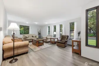 To the right upon entry is this lovely and spacious family room--tons of windows for green views and inviting daylight, new LVP flooring, and fresh paint!