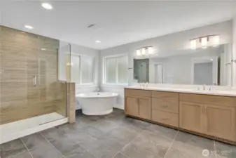 Spa inspired primary bathroom with a dual sink vanity, soaking tub, and spacious shower.