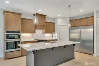 Stainless steel appliances including a deluxe refrigerator/freezer and double ovens.