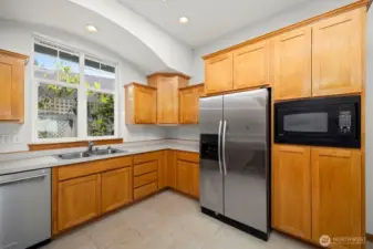 There is a built in microwave to the right of the refrigerator with pantry storage space above and below.
