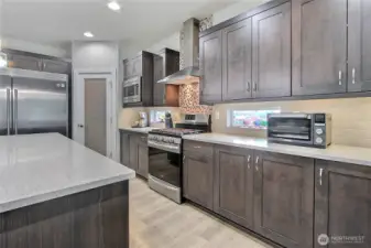 The space here is simply incredible! This kitchen showcases a 6-foot refrigerator and, just beyond the glass door, one incredible pantry—offering massive storage, style, and functionality all in one stunning, well-designed space.