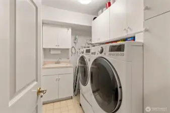 The laundry room includes a wash sink and front-load washer and dryer, making chores convenient and efficient. Newer water heater too!