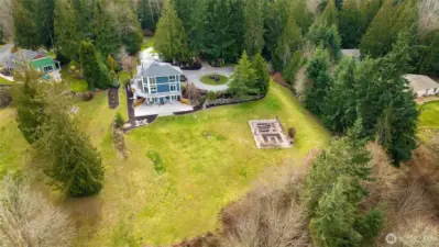 Aerial view of the rear of home with large open lawn areas and garden area