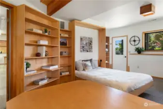 Entering the downstairs bedroom, with built in bookcases and desk,  a custom built queen-size Murphy bed, ensuite bath and direct exterior entrance.
