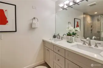 Primary bath with double sinks, tile floors and large mirror.