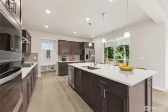 Large kitchen island with built in oven and microwave, soft close cabinets, and quartz countertops all standard. Photo of actual home with virtual staging.