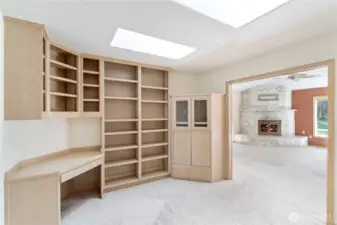 Office off of living room with built in cabinets and bookshelves.
